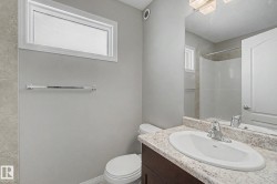 Bathroom featuring a dark wood-finish vanity with an undermount sink, a light speckled countertop, and a shower with tiled walls - 