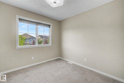 Bright room featuring a large window with white trim, light neutral wall paint, gray carpeting, and white baseboards - 