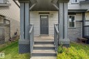 Front entry featuring a dark gray door with decorative glass, sheltered porch, and wood-finish steps - 315 Watt Boulevard Sw, Edmonton, AB 