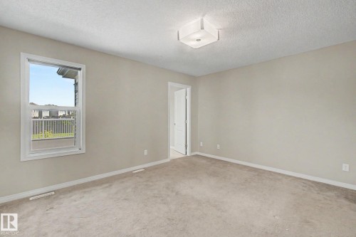 Spacious room featuring neutral carpeting, light-toned walls, and a multi-pane window with white trim - 315 Watt Boulevard Sw, Edmonton, AB 