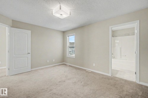 Carpeted room featuring a ceiling-mounted light fixture, a window with exterior views, and neutral wall tones - 315 Watt Boulevard Sw, Edmonton, AB 