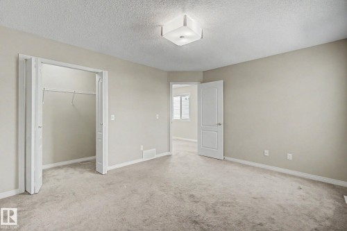 Carpeted interior room featuring neutral wall tones, white baseboards, and a semi-flush ceiling light fixture - 315 Watt Boulevard Sw, Edmonton, AB 