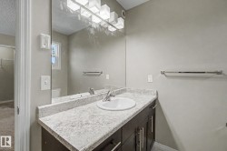 Bathroom vanity featuring a white oval sink, chrome faucet, and stone-look countertop - 