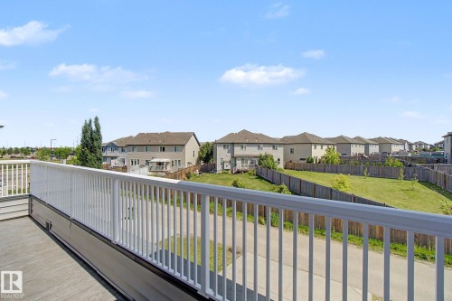 Spacious outdoor deck with white railing, grey composite decking, and light grey siding overlooking a paved path and green space - 315 Watt Boulevard Sw, Edmonton, AB 