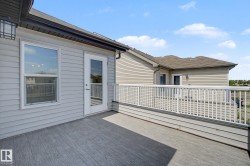 Spacious outdoor deck featuring wood-finish composite decking, white railing, and a glass-paneled door - 