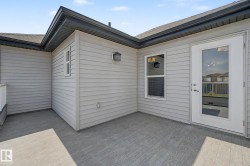 Outdoor patio featuring wood-finish decking, light gray siding, and an exterior door with glass paneling - 