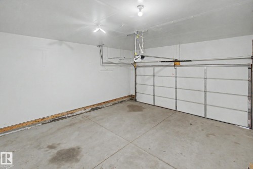 Spacious garage with concrete flooring, white walls, and an automatic garage door opener - 315 Watt Boulevard Sw, Edmonton, AB 