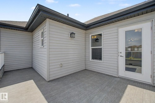 Outdoor patio featuring wood-finish decking, light gray siding, and an exterior door with glass paneling - 315 Watt Boulevard Sw, Edmonton, AB 