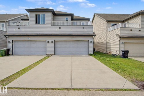 Modern multi-level exterior featuring light-colored siding, a two-car garage with individual doors, dual balconies with white railings, and a concrete driveway - 315 Watt Boulevard Sw, Edmonton, AB 