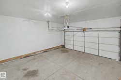 Spacious garage with concrete flooring, white walls, and an automatic garage door opener - 