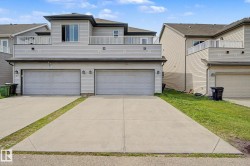 Modern multi-level exterior featuring light-colored siding, a two-car garage with individual doors, dual balconies with white railings, and a concrete driveway - 