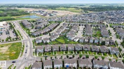 Modern suburban development featuring residential homes with diverse architectural styles, visible streets, and green spaces - 