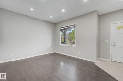 Open-concept living space with dark wood-finish flooring, recessed lighting, a large window with roller shades, and light gray wall tones - 