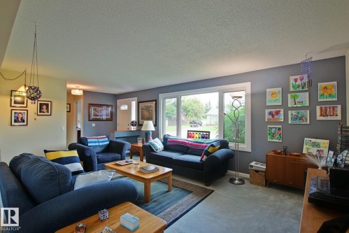 Spacious living area featuring a neutral color palette, large window, and light-colored flooring - 3536 104 Street Nw, Edmonton, AB - Indoor Photo Showing Living Room