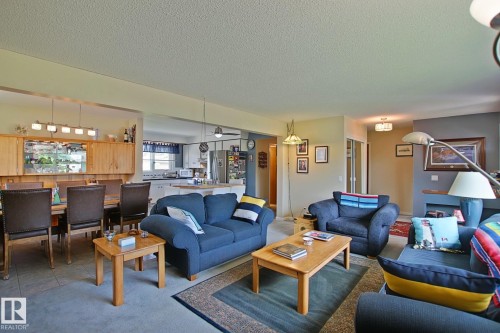 Spacious living area featuring carpet flooring, recessed shelving, and a bright kitchen with white cabinetry - 3536 104 Street Nw, Edmonton, AB - Indoor Photo Showing Living Room