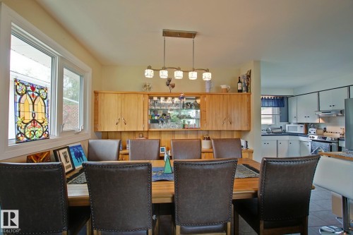 Dining area with a linear pendant light fixture, built-in display cabinetry, and a prominent stained-glass window panel - 3536 104 Street Nw, Edmonton, AB - Indoor Photo Showing Dining Room