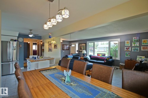 Open-concept living area featuring a wood-finish dining table, a spacious living room with large windows, and a kitchen area with a built-in island - 3536 104 Street Nw, Edmonton, AB - Indoor Photo Showing Other Room