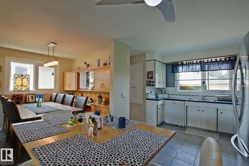 Kitchen and dining area featuring a breakfast bar, wood-finish cabinetry, a stainless steel refrigerator, and tiled flooring - 3536 104 Street Nw, Edmonton, AB - Indoor Photo Showing Dining Room