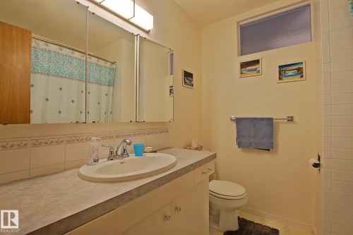 Bathroom featuring a vanity with an integrated sink, a large tri-fold mirrored medicine cabinet, and a chrome faucet - 3536 104 Street Nw, Edmonton, AB - Indoor Photo Showing Bathroom