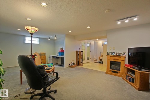 Spacious finished lower level with recessed lighting and neutral carpeting - 3536 104 Street Nw, Edmonton, AB - Indoor With Fireplace