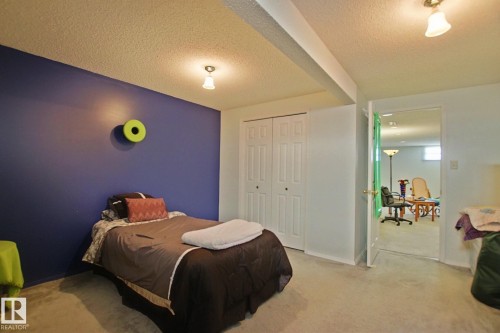 Carpeted room featuring a distinctive accent wall, bi-fold closet doors, and recessed ceiling lighting - 3536 104 Street Nw, Edmonton, AB - Indoor Photo Showing Bedroom