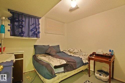 Room featuring painted concrete flooring, a window with horizontal blinds, and a built-in overhead light fixture - 3536 104 Street Nw, Edmonton, AB - Indoor Photo Showing Bedroom