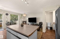 Kitchen island with a solid surface countertop, white cabinetry, and track lighting - 