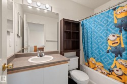 White bathroom vanity with a drop-in sink, neutral countertop, and a large wall-mounted mirror - 