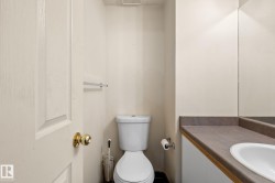 Compact powder room featuring a single vanity with an integrated sink, a full-width mirror, and a white toilet - 