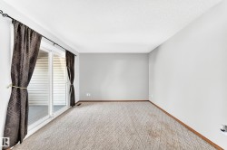Spacious room featuring light gray walls and patterned carpet flooring - 