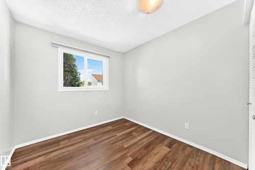 Interior room featuring wood-finish flooring, light grey walls, and white trim - 22 Woodvale Village Nw, Edmonton, AB - Indoor Photo Showing Other Room