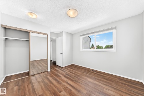 Spacious room featuring wood-finish flooring, light grey walls, and a large window - 22 Woodvale Village Nw, Edmonton, AB - Indoor Photo Showing Other Room