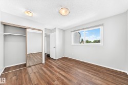 Spacious room featuring wood-finish flooring, light grey walls, and a large window - 