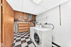 Utility area featuring a black and white checkerboard tile floor, drop ceiling, and wood-finish door - 