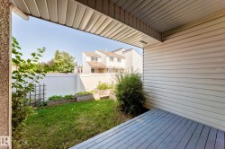 Covered outdoor deck with painted wood-finish flooring, bordered by a white privacy fence - 