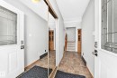 Entryway featuring two white doors with decorative glass inserts, an overhead light fixture, wood-finish baseboards, and a mirrored closet door - 22 Woodvale Village Nw, Edmonton, AB  - Indoor Photo Showing Other Room 