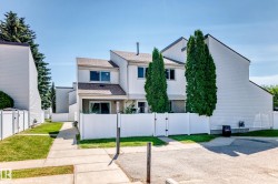 Two-story townhome featuring white siding and a brown shingled roof - 