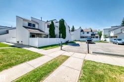 White siding townhome featuring a distinctive sloped roofline, second-story windows, and a private patio area - 