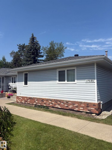 Ranch-style exterior featuring light-colored siding, a brick accent foundation, and multiple windows - 17520 Callingwood Road Nw, Edmonton, AB - Outdoor