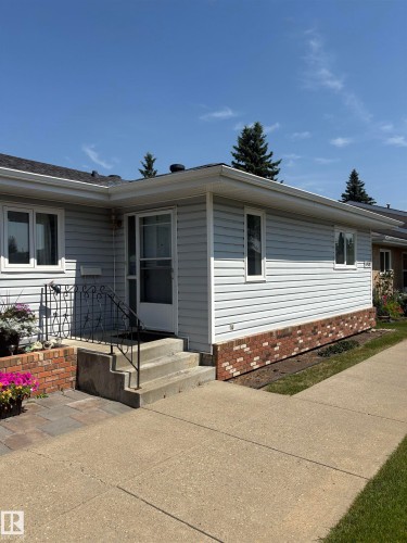 Exterior featuring light grey siding, brick detailing, a concrete walkway, and a concrete entry staircase with a metal handrail - 17520 Callingwood Road Nw, Edmonton, AB - Outdoor