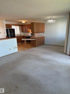 Open-concept living space featuring a kitchen with wood-finish cabinetry, a breakfast bar, and a black appliance package - 