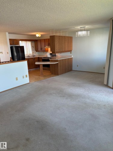 Kitchen area featuring wood-finish cabinetry, a breakfast bar, and an integrated electric range - 17520 Callingwood Road Nw, Edmonton, AB - Indoor