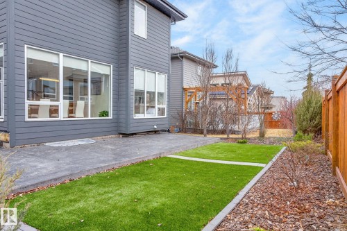 Exterior showcasing grey horizontal siding, a concrete patio, and a section of artificial turf - 1313 Hainstock Way Sw, Edmonton, AB - Outdoor With Deck Patio Veranda