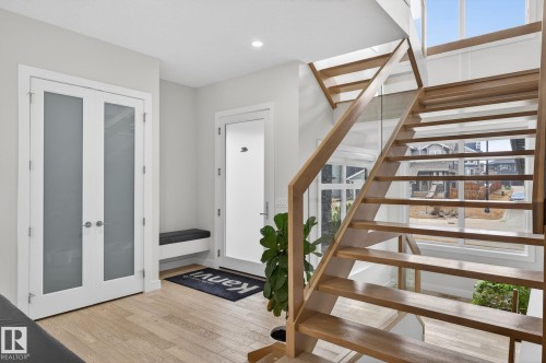 Floating wood-finish staircase with glass panel railing - 1313 Hainstock Way Sw, Edmonton, AB - Indoor Photo Showing Other Room