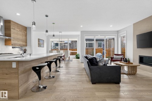Open-concept living area featuring light wood-finish flooring throughout - 1313 Hainstock Way Sw, Edmonton, AB - Indoor With Fireplace