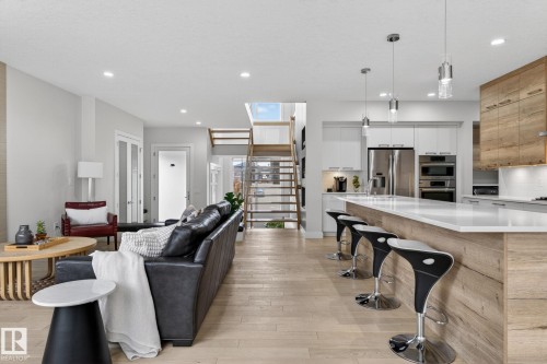 Open-concept living area featuring light wood-finish flooring throughout - 1313 Hainstock Way Sw, Edmonton, AB - Indoor Photo Showing Kitchen With Upgraded Kitchen