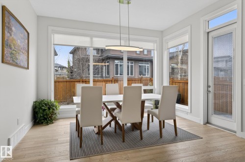 Dining area featuring wood-finish flooring and ample natural light from large windows - 1313 Hainstock Way Sw, Edmonton, AB - Indoor Photo Showing Dining Room