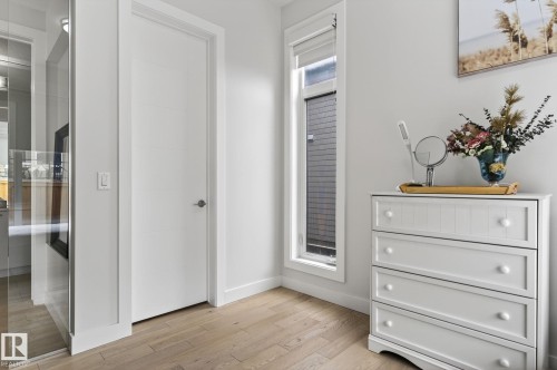 Warm wood-finish flooring complements crisp white walls and trim - 1313 Hainstock Way Sw, Edmonton, AB - Indoor Photo Showing Other Room