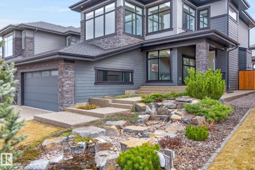 Modern gray exterior featuring a stone facade and black-framed windows - 1313 Hainstock Way Sw, Edmonton, AB - Outdoor