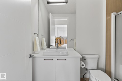 White vanity with a rectangular vessel sink, wall-mounted mirror, and chrome fixtures - 1313 Hainstock Way Sw, Edmonton, AB - Indoor Photo Showing Bathroom